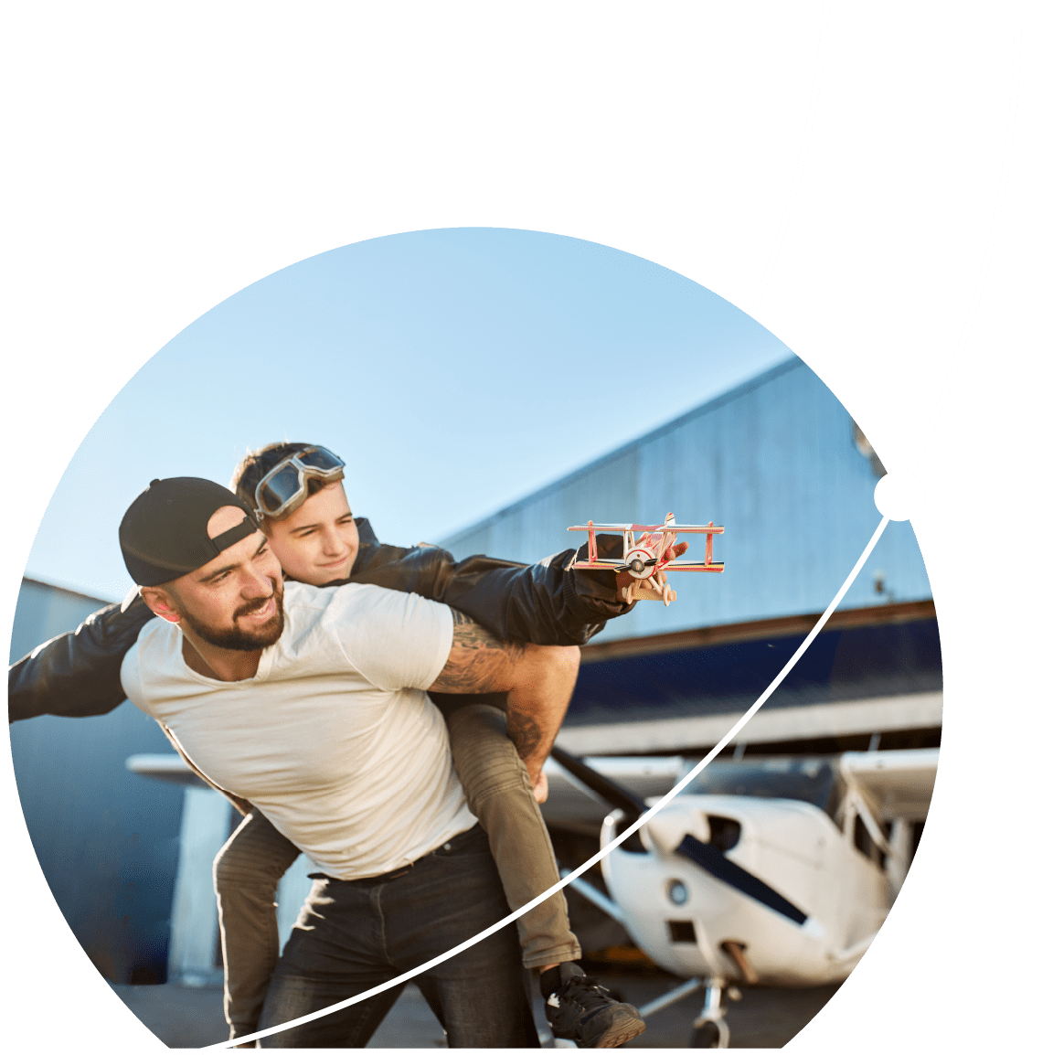 A father and son outside of an airport hangar, standing in front of a plane