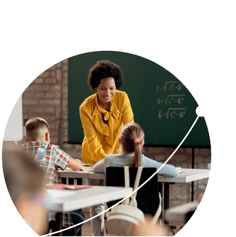 Happy black elementary school teacher taking to her students in the classroom.