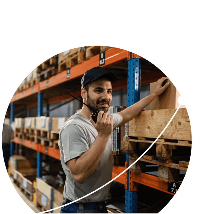 Happy warehouse worker talking on walkie-talkie in a storage room.