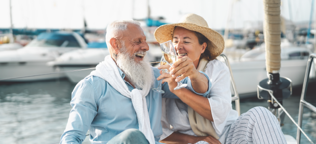 Senior couple toasting champagne on yacht - Happy elderly people having fun celebrating wedding anniversary on boat trip - Love relationship and travel lifestyle concept
