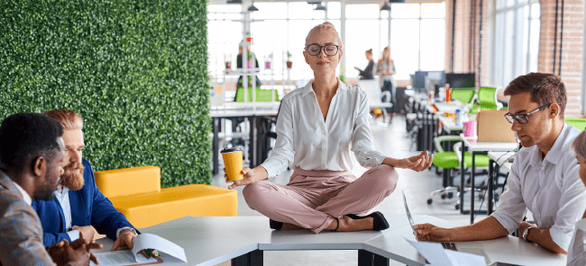 Women sitting on a table in an office doing a yoga resting pose