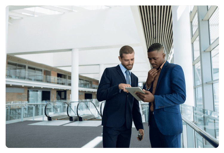 Two businessmen stand using tablet at work